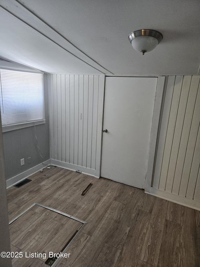 unfurnished room with wood-type flooring and lofted ceiling