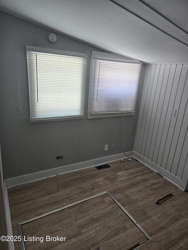 unfurnished room with dark hardwood / wood-style flooring, vaulted ceiling, and a wealth of natural light