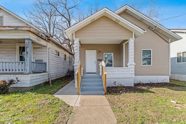 bungalow with central AC unit, covered porch, and a front lawn