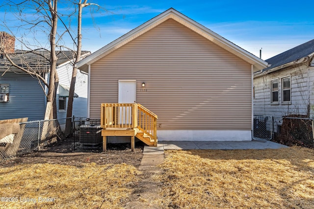 rear view of property with central air condition unit and a lawn