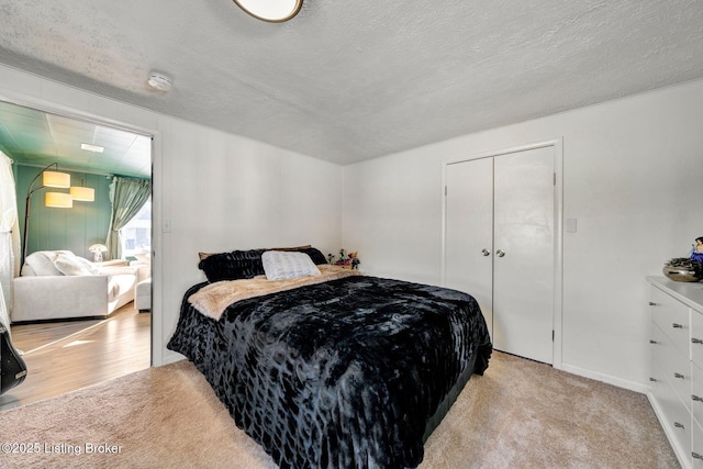 bedroom with light colored carpet, a textured ceiling, and a closet