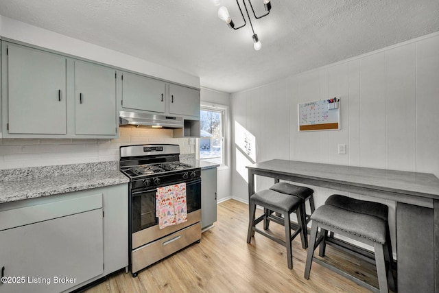 kitchen featuring light wood-type flooring, stainless steel range with gas stovetop, and a textured ceiling