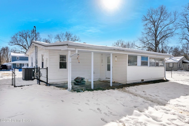 snow covered rear of property featuring central AC unit