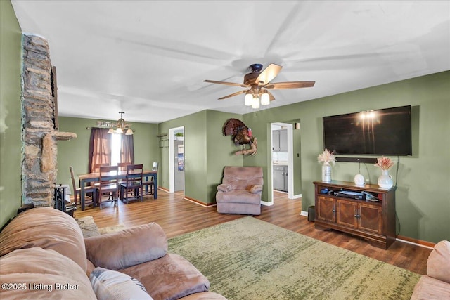 living room featuring ceiling fan with notable chandelier and hardwood / wood-style flooring