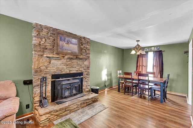 living room featuring wood-type flooring, a wood stove, and a chandelier