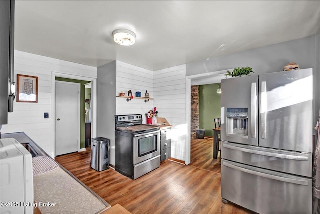 kitchen with dark hardwood / wood-style flooring, wood walls, and appliances with stainless steel finishes