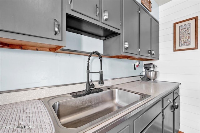 kitchen with sink, wood walls, and gray cabinetry