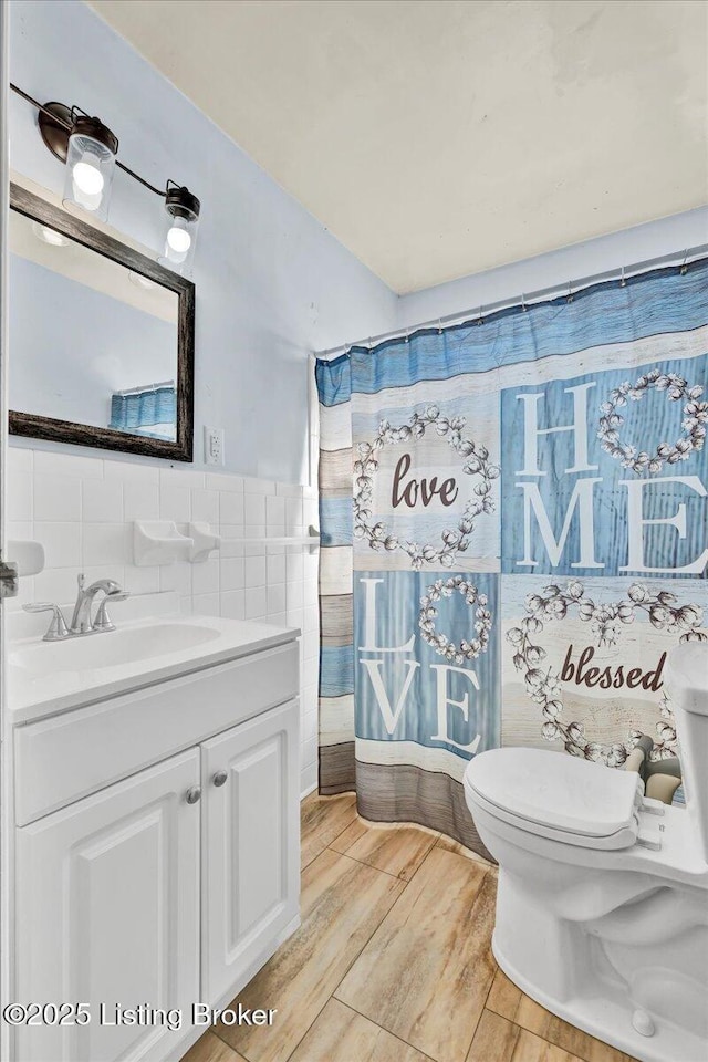 bathroom featuring tile walls, toilet, curtained shower, and vanity