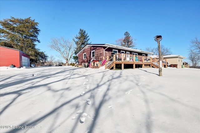 snow covered rear of property featuring a garage