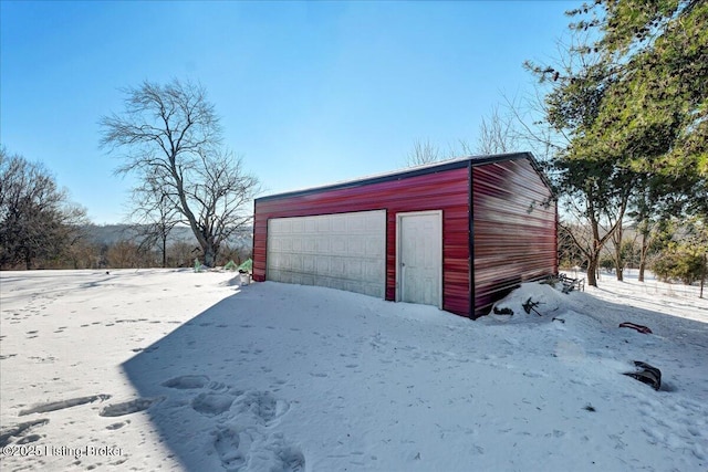 snow covered structure featuring a garage