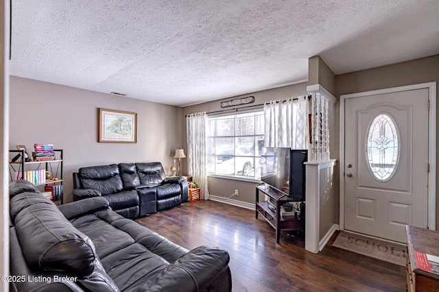 living room with a textured ceiling and dark hardwood / wood-style floors