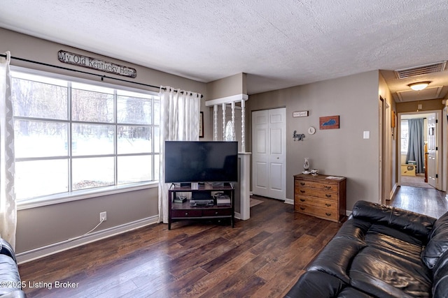 living room with a healthy amount of sunlight, dark hardwood / wood-style flooring, and a textured ceiling