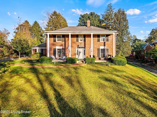 neoclassical home featuring a front lawn