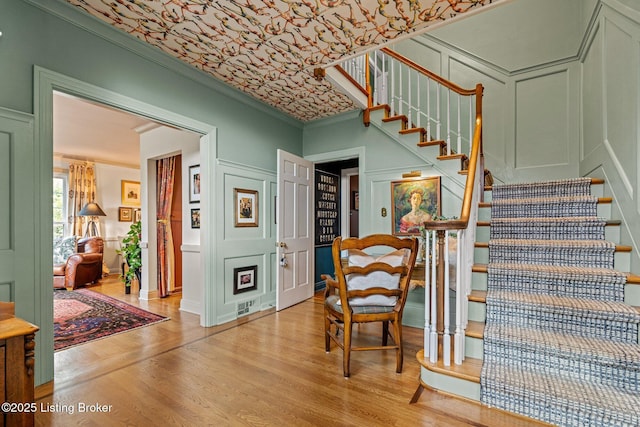 stairway with hardwood / wood-style flooring and ornamental molding