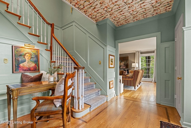 stairway with hardwood / wood-style floors and ornamental molding