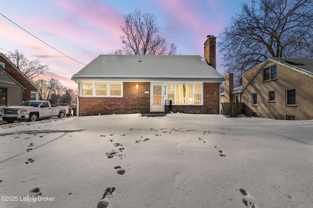 view of front of house with brick siding and a chimney