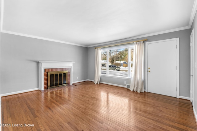 unfurnished living room with a brick fireplace, ornamental molding, and hardwood / wood-style floors