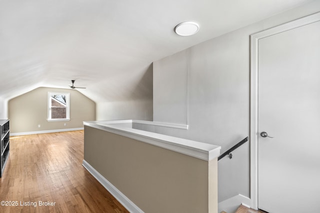 hallway with vaulted ceiling and hardwood / wood-style floors