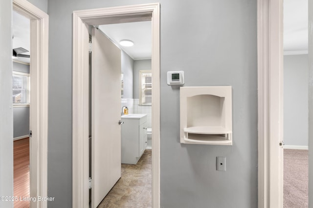 hallway with sink, tile walls, a healthy amount of sunlight, and crown molding