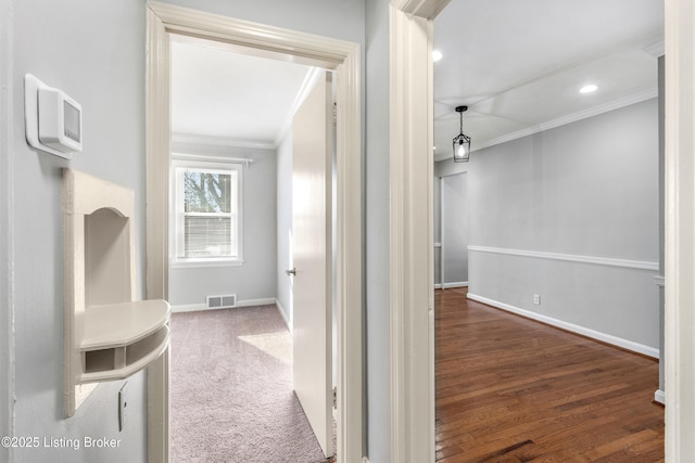 hall featuring crown molding and dark carpet