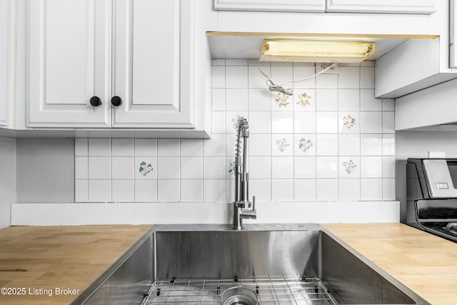 kitchen with white cabinets, wooden counters, sink, and decorative backsplash