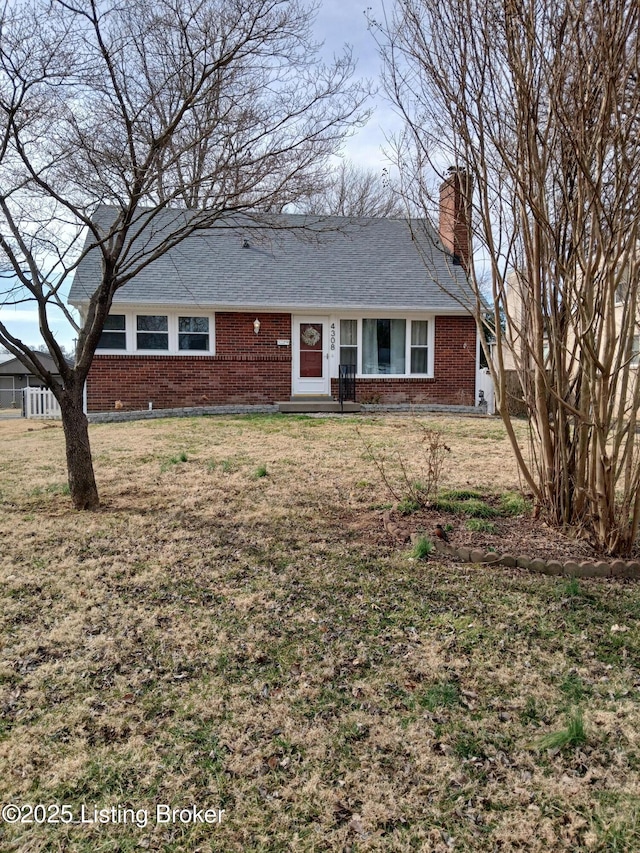 ranch-style home featuring brick siding, a chimney, and a front lawn