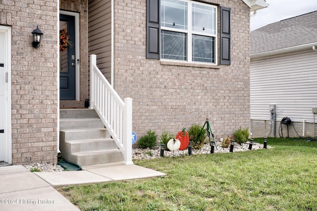 view of exterior entry featuring a lawn