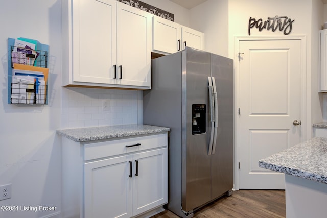 kitchen with white cabinets, stainless steel refrigerator with ice dispenser, and light stone counters