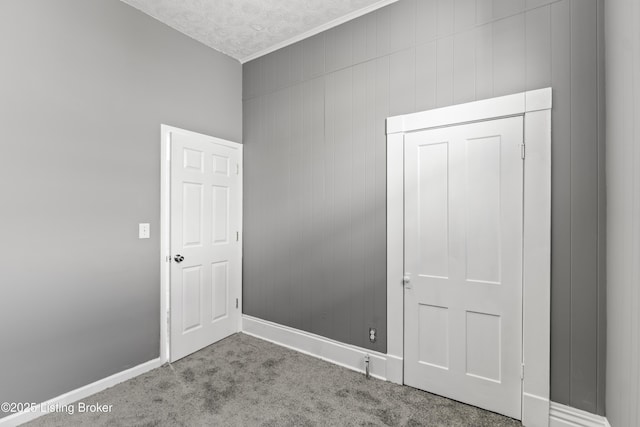 carpeted empty room with a textured ceiling and wood walls