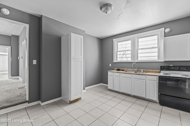 kitchen featuring range with electric stovetop, white cabinetry, sink, and light tile patterned flooring