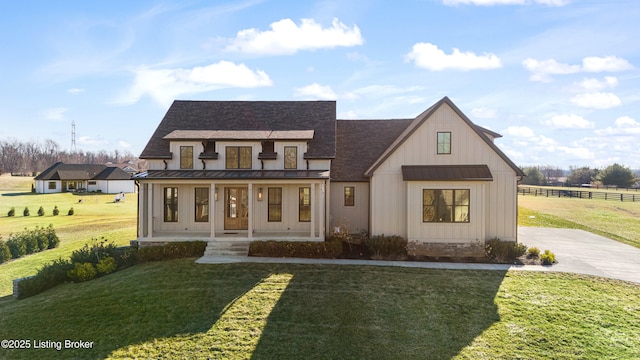 modern farmhouse style home with metal roof, covered porch, fence, a front lawn, and a standing seam roof