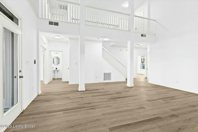 unfurnished living room with hardwood / wood-style floors, a high ceiling, and sink