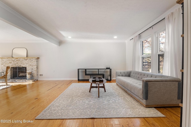 living area featuring ornamental molding, a fireplace, baseboards, and wood finished floors