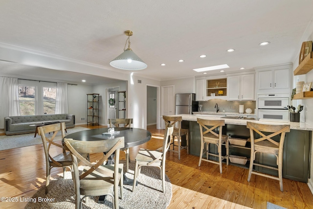 dining room with recessed lighting, light wood-style flooring, crown molding, and baseboards