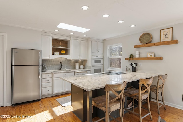 kitchen with open shelves, white appliances, white cabinetry, and a sink