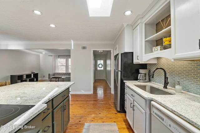 kitchen featuring black electric stovetop, light wood-style flooring, white dishwasher, white cabinets, and a sink