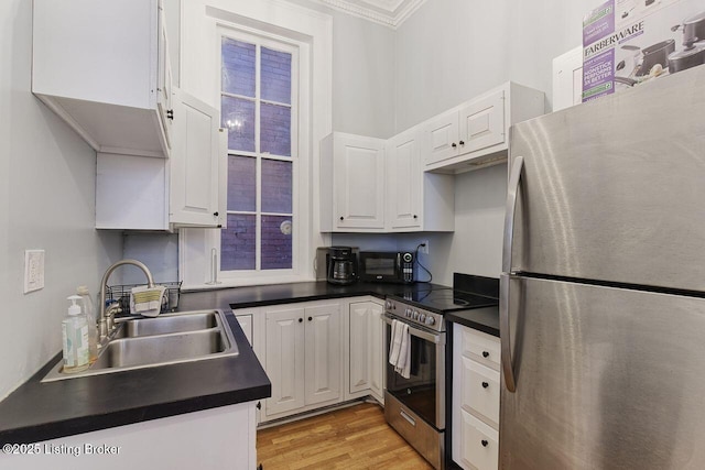 kitchen with white cabinetry, sink, light hardwood / wood-style floors, appliances with stainless steel finishes, and ornamental molding