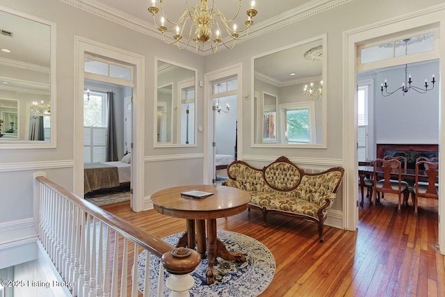 living area with crown molding, hardwood / wood-style floors, and a notable chandelier