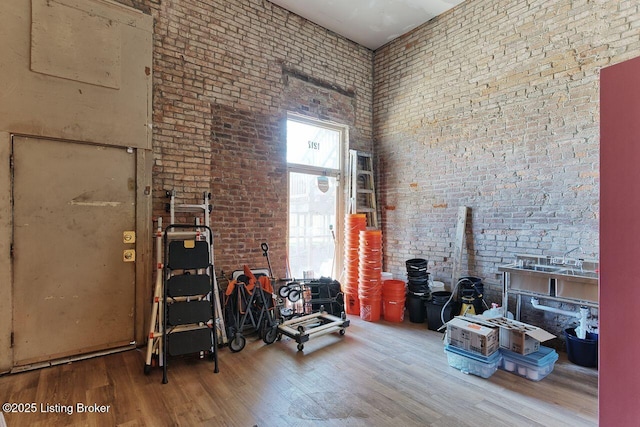 interior space featuring hardwood / wood-style flooring, a high ceiling, and brick wall