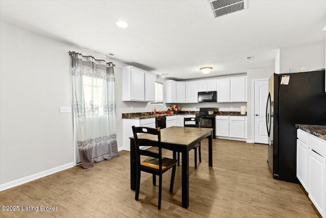 kitchen with white cabinets, black appliances, and light hardwood / wood-style flooring