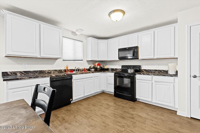 kitchen with a textured ceiling, white cabinets, black appliances, light hardwood / wood-style floors, and sink