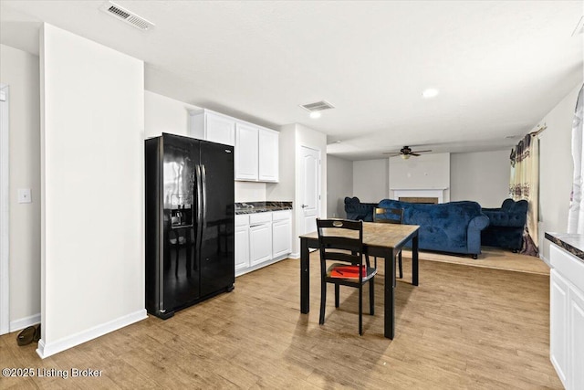 kitchen with ceiling fan, white cabinets, light hardwood / wood-style flooring, and black fridge