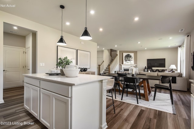 kitchen featuring pendant lighting, white cabinets, dark hardwood / wood-style floors, light stone countertops, and a kitchen island