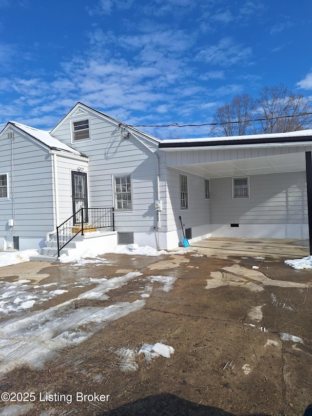 snow covered rear of property with a carport