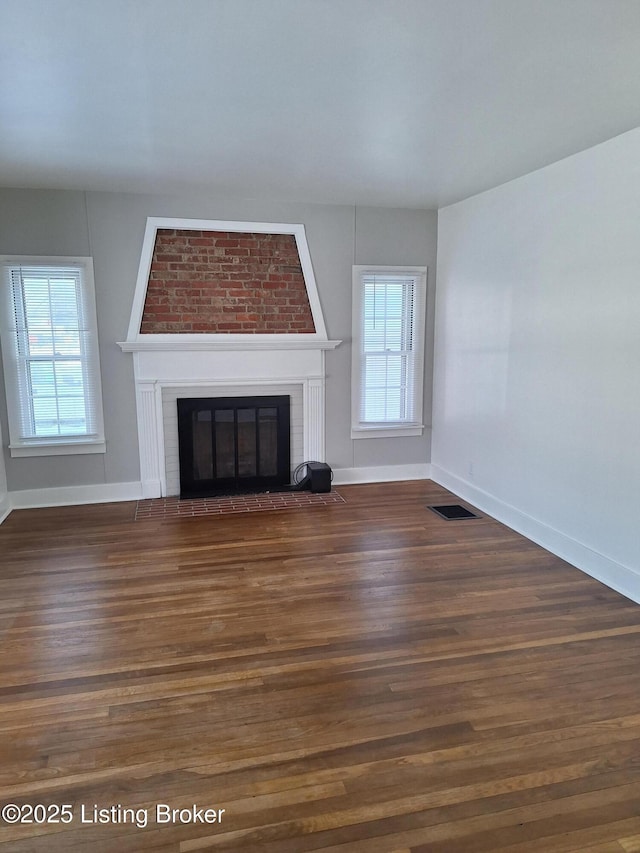 unfurnished living room featuring dark hardwood / wood-style floors and a brick fireplace