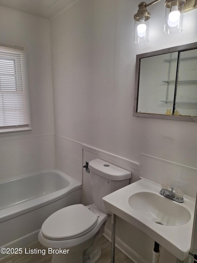 bathroom featuring a washtub, toilet, and sink