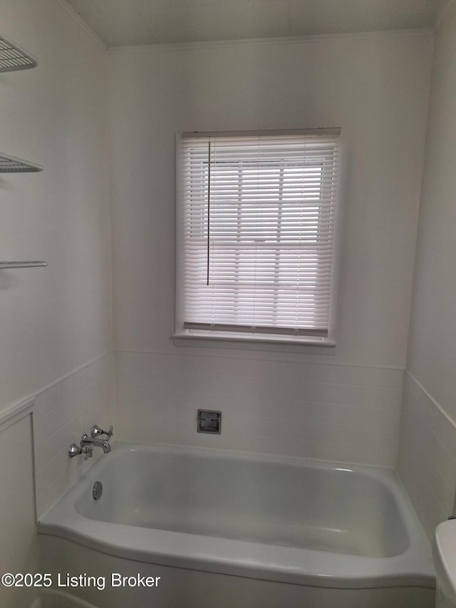 bathroom with a tub to relax in and toilet