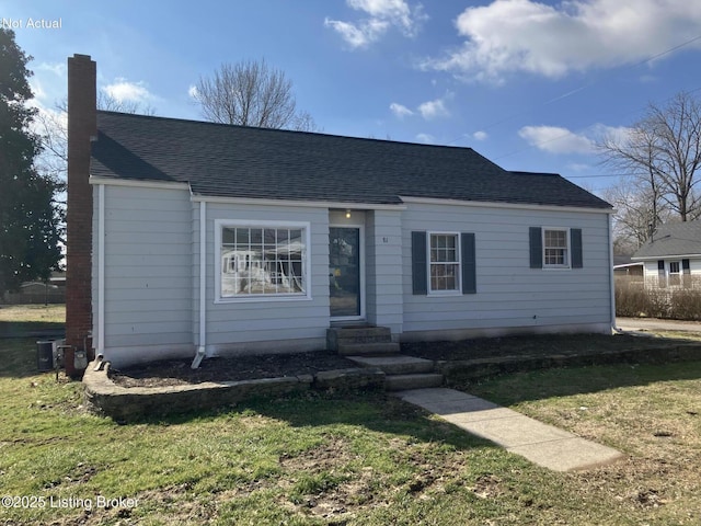 view of front of house with entry steps, a front yard, a chimney, and roof with shingles