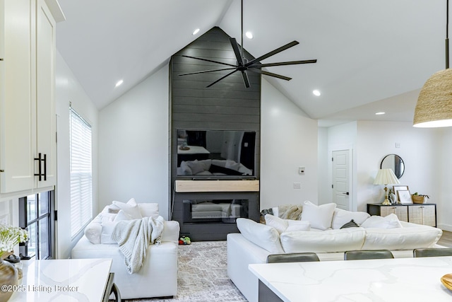 living room featuring a large fireplace, ceiling fan, and lofted ceiling