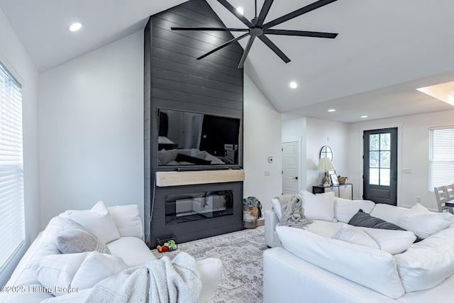 living room with a large fireplace, a wealth of natural light, and lofted ceiling